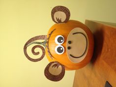 a pumpkin shaped like a monkey with ears and eyes on top of a wooden table