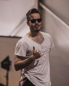 a man in white shirt and black pants giving a peace sign with his right hand