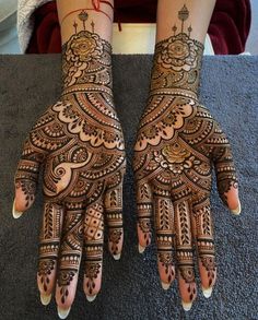 two hands with henna tattoos on them, one is showing off the intricate design