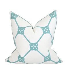 a white and blue pillow with an intricate design on the front, sitting on a white surface