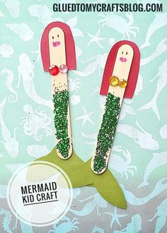 two little mermaids made out of popsicle sticks with glitter on them, sitting next to each other