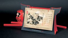 there is a red vase next to a chinese calendar