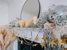 a fireplace mantel with candles, flowers and decorations in front of a mirror on the mantle