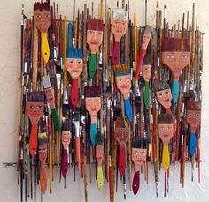 a group of people's faces made out of paintbrushes on a wall