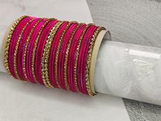 "Medium Stack of Dark Pink & Golden Stones Bangles Set- Beautiful occasion wear jewellery The perfect fusion of tradition and style, designed to elevate your outfit with elegance and charm. This Bangle set is made for two hands and contains 17 pieces in each set. If you want to match the design shown in the picture in single hand, be sure to select a quantity of 2. Notes: Sizes for bangles are Indian sizes so check your exact size as shown in picture before placing and order. Create beautiful me Bangle For Diwali Celebration, Pink Bangle Jewelry For Diwali, Festive Fusion Style Bangle For Celebrations, Festive Fusion Bangle For Celebrations, Adjustable Pink Bracelet For Diwali, Pink Bollywood Bracelets For Celebration, Pink Bollywood Celebration Bracelets, Festive Pink Jewelry For Puja, Pink Adjustable Jewelry For Puja