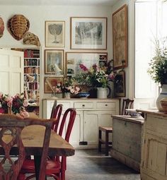 a dining room table with chairs and pictures on the wall above it, in front of a bookshelf