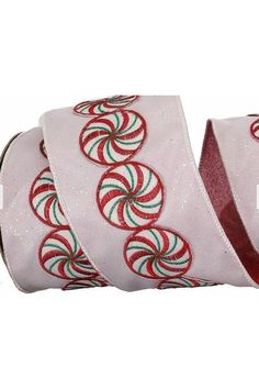 a roll of white ribbon with red and green designs on it, sitting next to each other