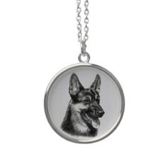 a black and white photo of a german shepherd dog on a silver plated necklace