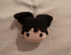 a small crocheted keychain with a black and white face on it