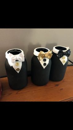 three black vases with white and gold bow ties