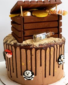 a cake with chocolate icing and decorations on it's sides, including a pirate chest