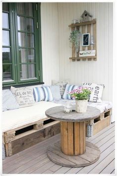 a wooden bench sitting on top of a wooden floor next to a table with flowers