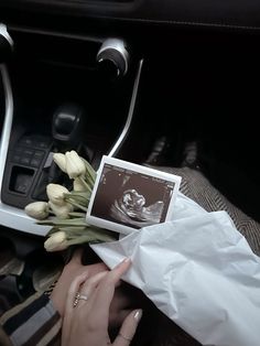 a woman is holding flowers in her hand while she sits in the car with an x - ray