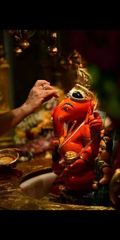 a statue of the hindu god ganesh is being held up by a person's hand