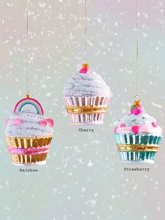 three cupcake ornaments hanging from strings in the snow