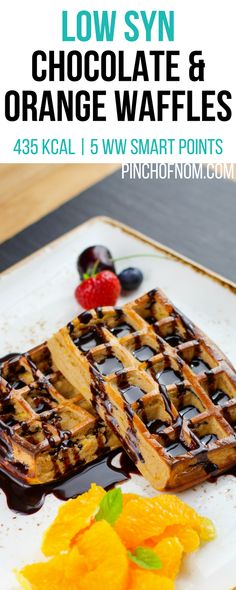 some waffles are sitting on a plate with orange slices and chocolate drizzle