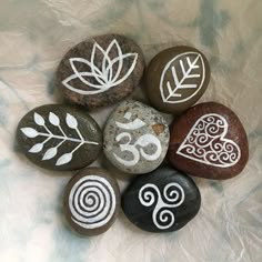 six rocks with white designs on them