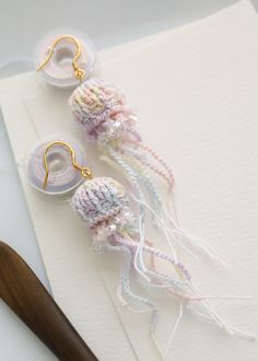 two crocheted jellys sitting on top of a piece of paper next to a pair of scissors