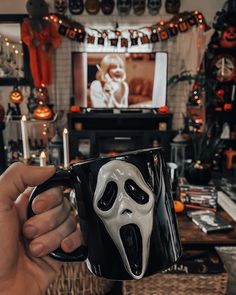 a person holding a black and white coffee mug with a ghost face on it