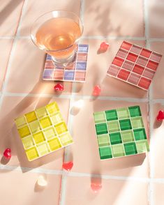 three different colored tiles on the floor next to a glass with liquid and candy candies