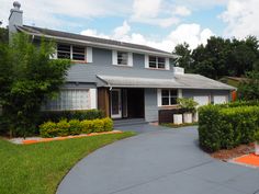 a grey house with trees and bushes around it