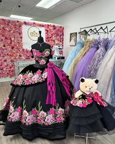 a dress with flowers on it and a teddy bear sitting in front of the dress