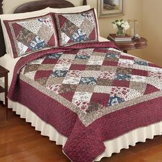 a bed with a red and white quilted bedspread on top of it