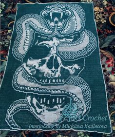 a skull and snake cross stitched onto a green blanket