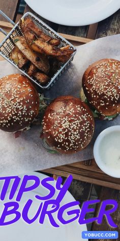 three burgers and some fries sitting on a table with the words tipsy burger