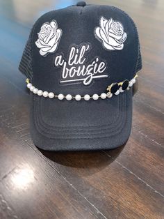 Rock a boujee style with our A Lil Boujee Trucker Hat. This trucker hat features a sassy patch that says "a lil boujee", rose patches for a touch of elegance, a pearl accent chain for added flair, and a gold & black sunglass pin. Stand out in the crowd and elevate your look with this one-of-a-kind hat. Trendy Adjustable Snapback Hat, Trendy Adjustable Party Trucker Hat, Trendy Adjustable Trucker Hat For Parties, Trendy Adjustable Trucker Hat, Trendy Snapback Hat For Party, Trendy Snapback Hat As Gift, Trendy Trucker Hat Gift, Trendy Trucker Hat As Gift, Trendy Adjustable Trucker Hat As Gift