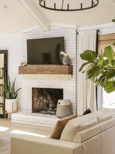 a living room with a white brick fireplace and tv on the mantel above it