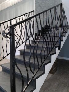 an iron stair railing with handrails in a home staircase area that is painted white and gray