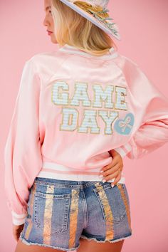 Gear up for the big game in our pink satin GAME DAY READY varsity jacket! With blue striped letters and a beaded bow heart patch, you'll stand out on the sidelines. Plus, the soft satin fabric will keep you comfortable and stylish all day long. Are you ready?! All orders are currently shipping within 14 business days. To receive item quicker, expedited shipping is available at checkout. Spring Varsity Jacket With Letter Embroidery, Pink Varsity Jacket For College, Sporty Pink Varsity Jacket For Fall, Pink Varsity Jacket For College In Fall, Pink Sporty Varsity Jacket For Fall, Collegiate Varsity Jacket For Game Day, Collegiate Varsity Jacket With Baseball Collar For Spring, Sporty Pink Varsity Jacket For Spring, Pink Varsity Jacket With Letter Print For Fall