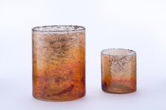 two glass vases sitting next to each other on a white surface