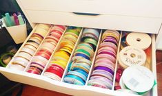 an open drawer filled with lots of different colored ribbons and spools of thread