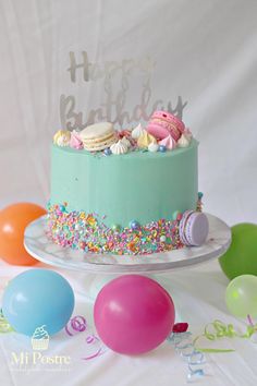 a birthday cake with sprinkles and balloons