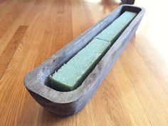 a wooden bench that has some kind of green substance in the middle of it on top of a hard wood floor