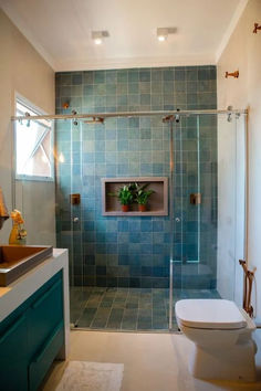 a bathroom with a toilet, sink and shower stall is shown in blue tile on the walls