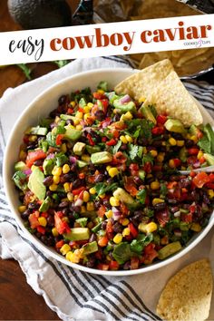 a bowl filled with black beans, corn and avocado next to tortilla chips