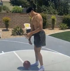 a shirtless man playing with a ball on a basketball court