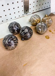 five metal ornaments sitting on top of a piece of cardboard next to a door handle