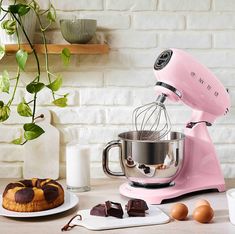 a pink mixer sitting on top of a counter next to some chocolates and eggs