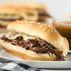 a close up of a sandwich on a plate with some dipping sauce in the background