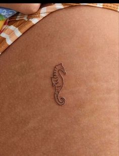 a close up of a person's stomach with a sea horse tattoo on it