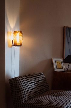 a living room with a couch, lamp and pictures on the wall in front of it