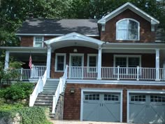 a large brown house with two garages and stairs leading to the upper level balcony