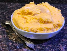 a bowl filled with mashed potatoes sitting on top of a counter next to a spoon