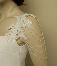 the back of a white dress with pearls and lace on it