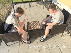 two young men sitting on chairs playing chess