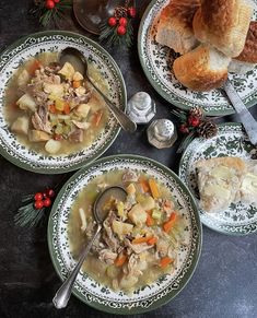 three plates filled with soup and bread on top of a black countertop next to silverware